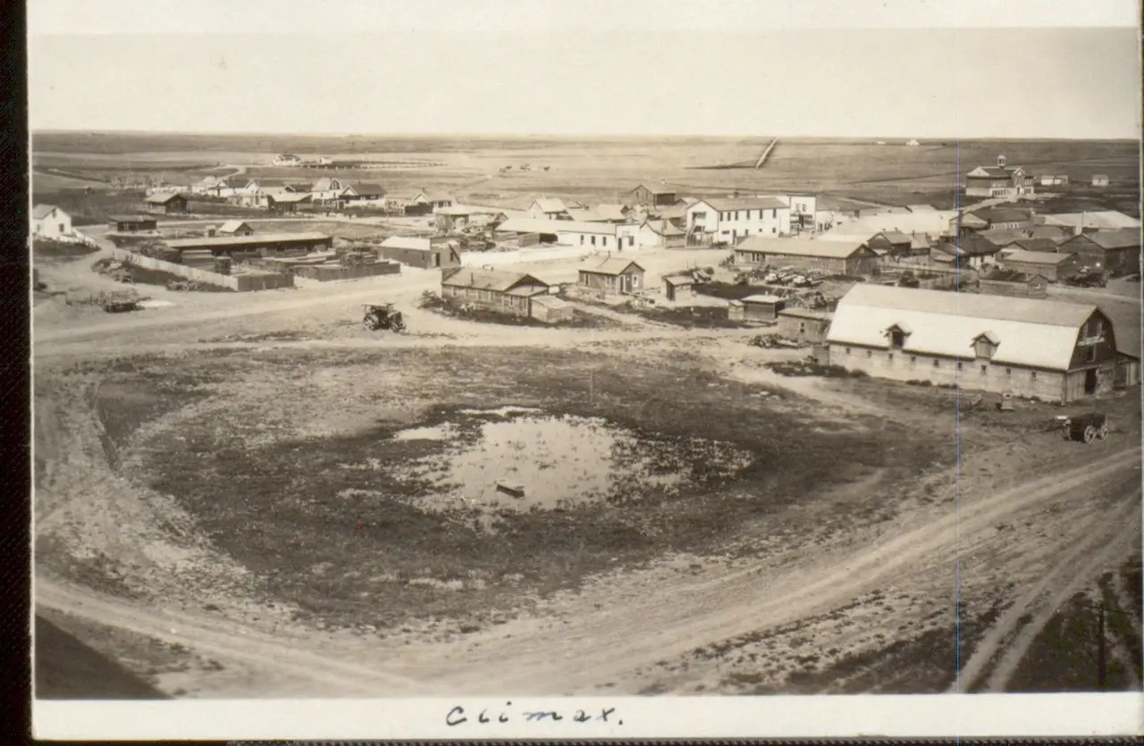 Aerial view of Climax with early buildings and a slough, about 1915